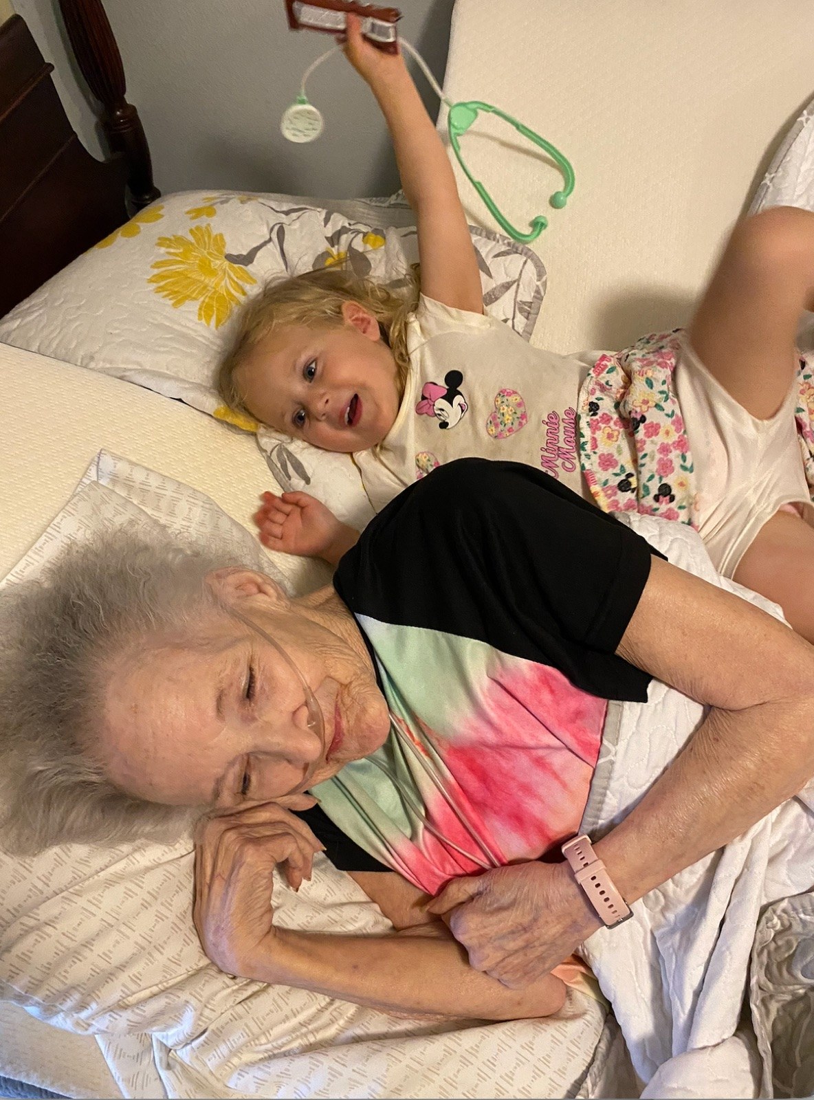 My daughter lying on a bed next to her great-grandmother